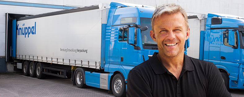 Lächelnder Fahrer vor geparktem Knüppel-LKW am Lagerdock